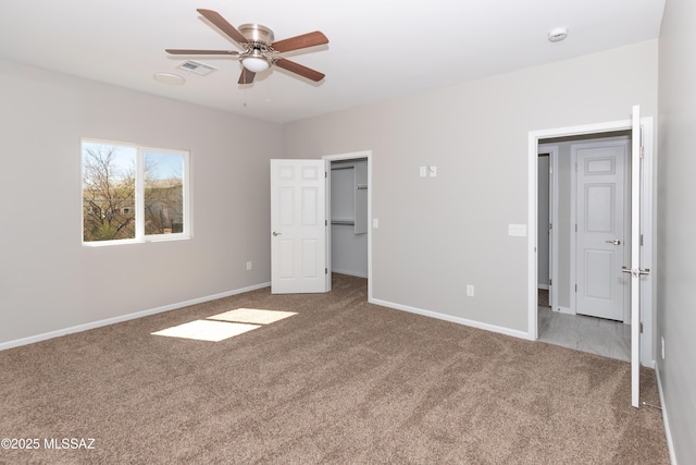 unfurnished bedroom with a ceiling fan, carpet, visible vents, baseboards, and a walk in closet