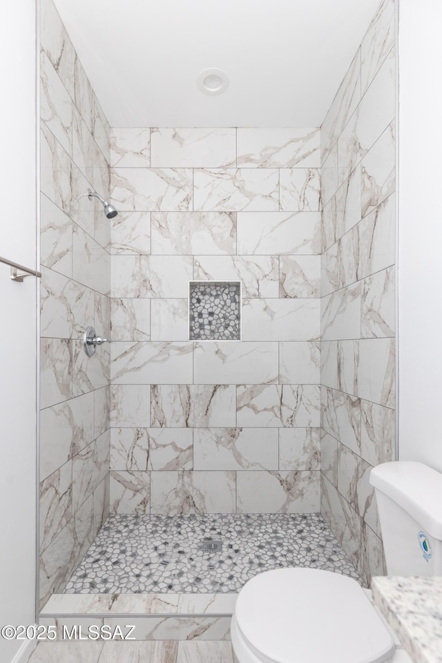 bathroom with toilet and tiled shower