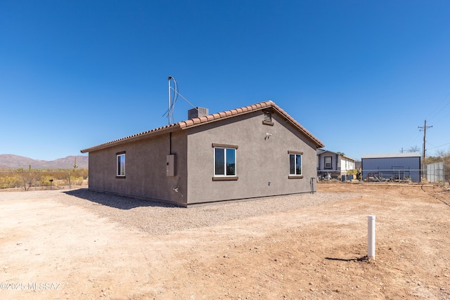 rear view of property with central AC unit, stucco siding, a mountain view, and a tile roof