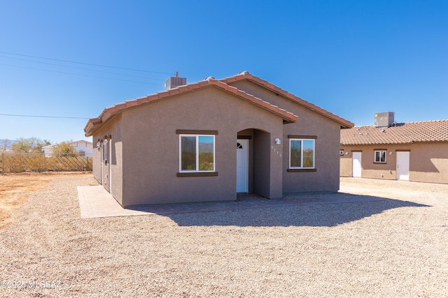 back of house featuring a tiled roof, stucco siding, central AC unit, and fence