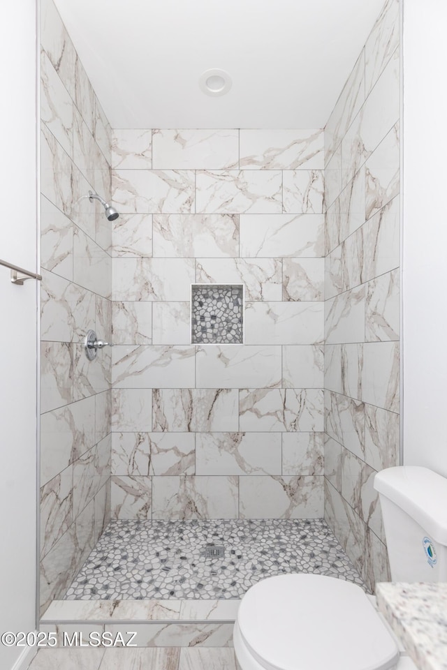 bathroom with tiled shower and toilet