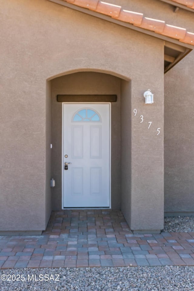 property entrance with stucco siding and a tiled roof