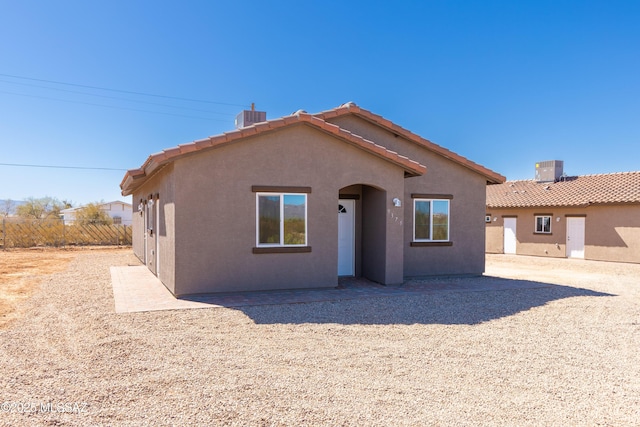 view of front of home with a tiled roof, fence, central air condition unit, and stucco siding