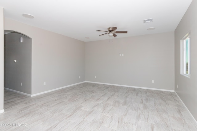 unfurnished room with arched walkways, ceiling fan, baseboards, and visible vents