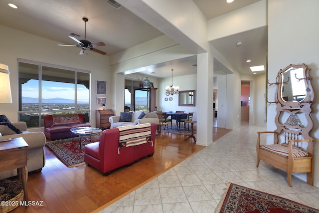 living room with ceiling fan with notable chandelier, light wood-style flooring, and visible vents