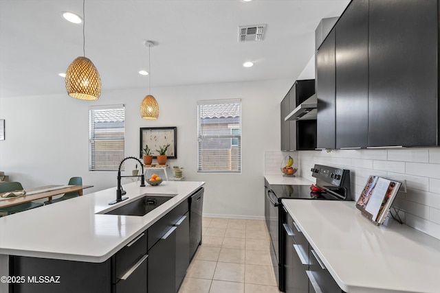 kitchen with light countertops, visible vents, dark cabinetry, a sink, and black appliances