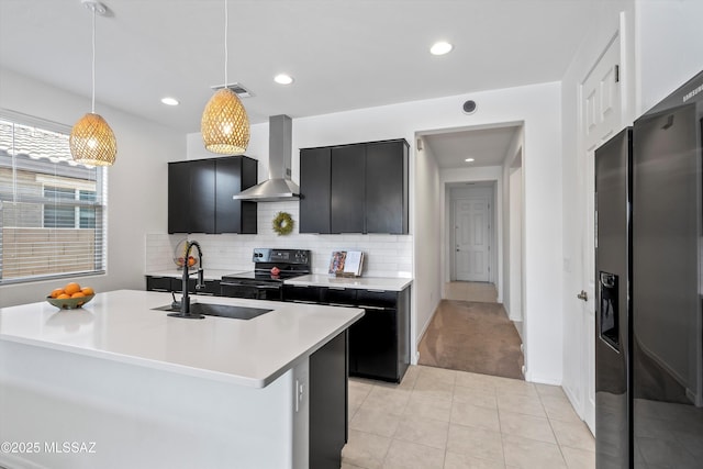 kitchen with a sink, dark cabinetry, electric range, wall chimney exhaust hood, and visible vents