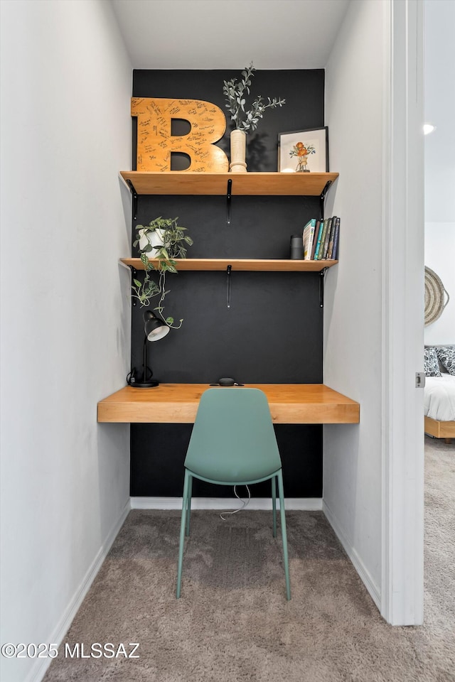 home office with built in study area, carpet floors, and baseboards