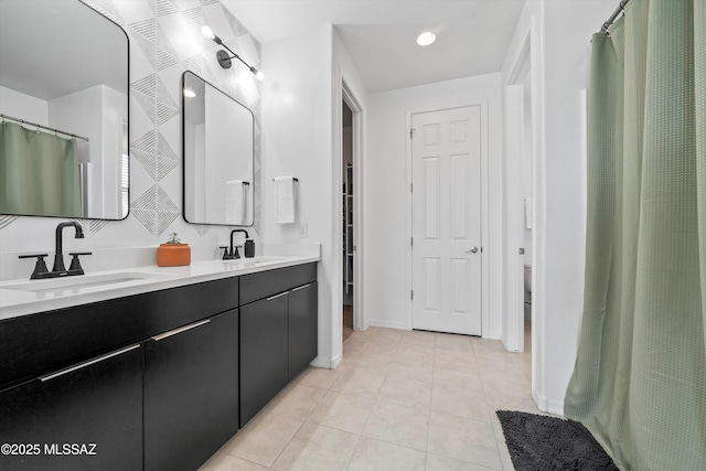 full bath with tile patterned floors, baseboards, a sink, and double vanity