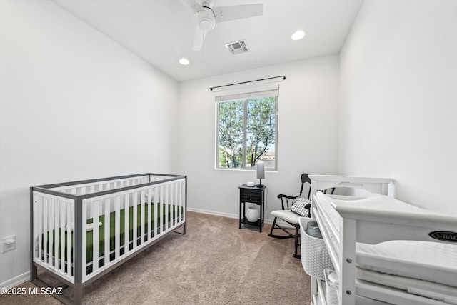 carpeted bedroom featuring recessed lighting, visible vents, a crib, and baseboards