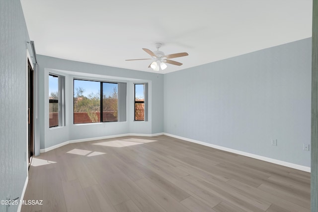 empty room featuring wood finished floors, a ceiling fan, and baseboards