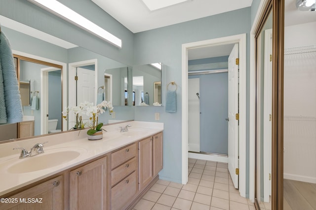 full bath with a sink, a shower stall, toilet, and tile patterned floors