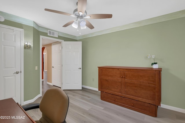 office with arched walkways, ceiling fan, visible vents, baseboards, and light wood-style floors