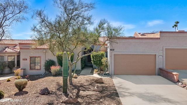 view of front of house featuring concrete driveway, a tiled roof, an attached garage, and stucco siding