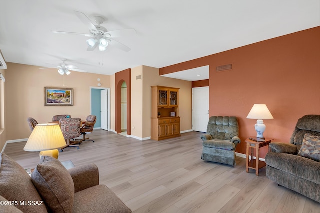 living area with ceiling fan, light wood finished floors, visible vents, and baseboards