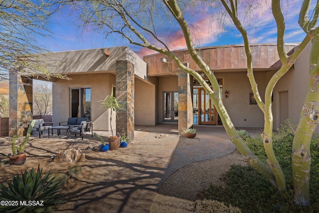 back of property with a patio area, stucco siding, french doors, and an outdoor hangout area