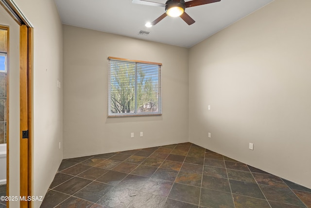 empty room featuring ceiling fan, visible vents, and stone finish flooring