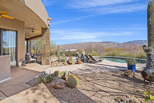 view of patio featuring an outdoor pool, a mountain view, and a ceiling fan