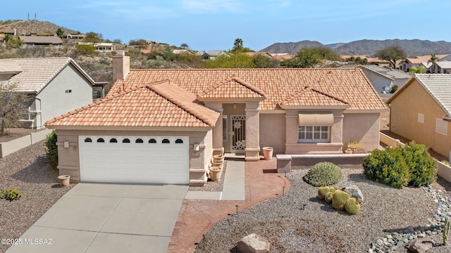 view of front facade featuring stucco siding, a chimney, concrete driveway, a garage, and a mountain view