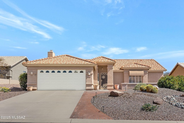 mediterranean / spanish-style house with an attached garage, a tile roof, stucco siding, a chimney, and driveway