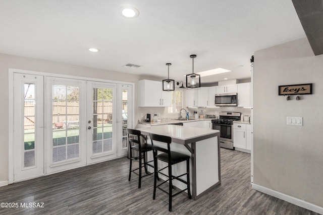 kitchen with visible vents, dark wood-style floors, stainless steel appliances, white cabinetry, and a sink