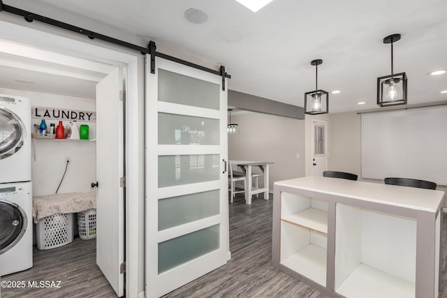 kitchen featuring a barn door, stacked washer and clothes dryer, wood finished floors, pendant lighting, and recessed lighting