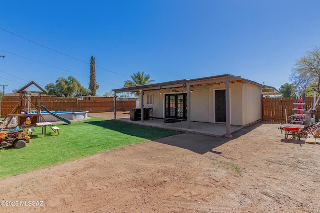 rear view of house with a fenced in pool, french doors, a lawn, a patio area, and a fenced backyard