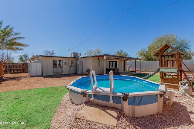 view of swimming pool with a fenced backyard, a playground, a fenced in pool, and a yard