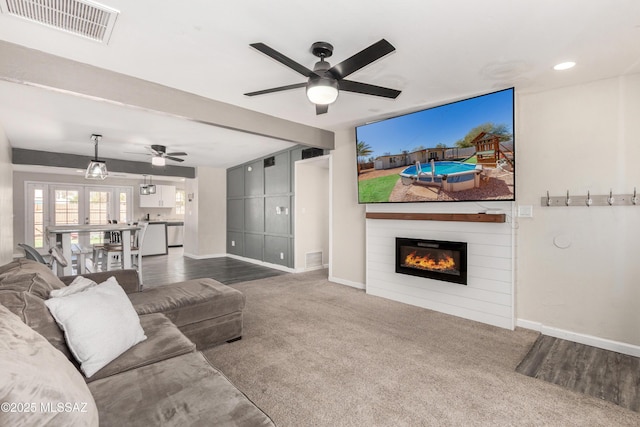 living room with carpet, visible vents, baseboards, and a glass covered fireplace