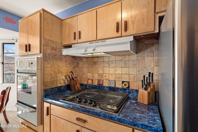 kitchen featuring a warming drawer, under cabinet range hood, dark countertops, tasteful backsplash, and appliances with stainless steel finishes