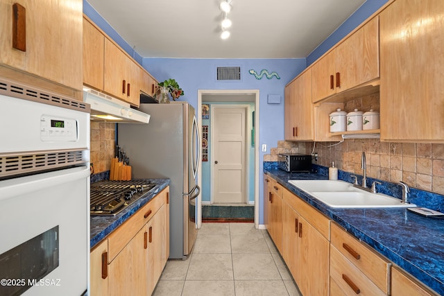 kitchen featuring visible vents, under cabinet range hood, light tile patterned floors, stainless steel gas stovetop, and a sink