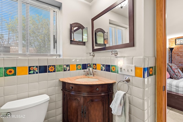 ensuite bathroom featuring ensuite bath, vanity, toilet, and tile walls