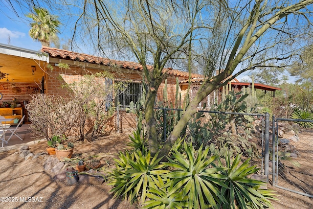 exterior space featuring a patio area, a tiled roof, fence, and brick siding