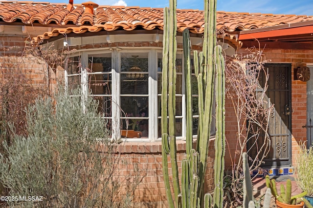 view of property exterior with brick siding and a tile roof