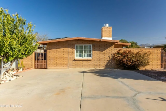 exterior space with brick siding, a chimney, a gate, and fence