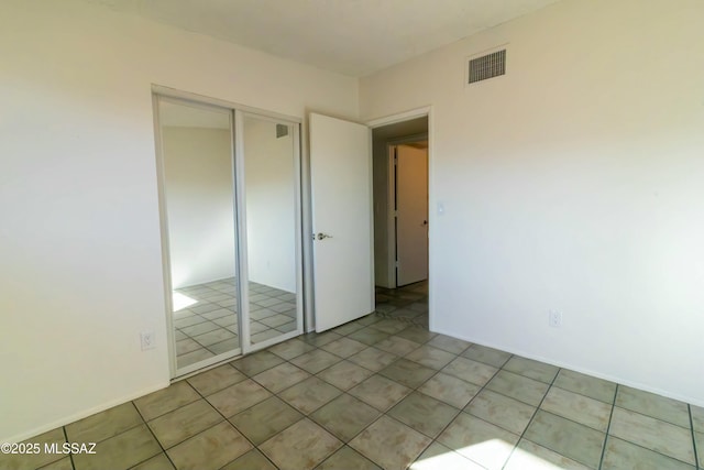 unfurnished bedroom with tile patterned floors, visible vents, and a closet