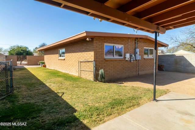 view of property exterior with a gate, brick siding, a lawn, and fence