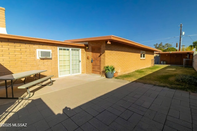 back of house with a yard, a patio, brick siding, and an outdoor structure