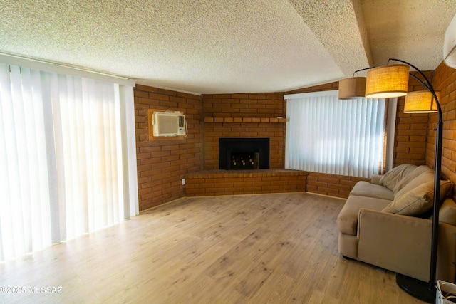 living room with a textured ceiling, brick wall, wood finished floors, and a fireplace