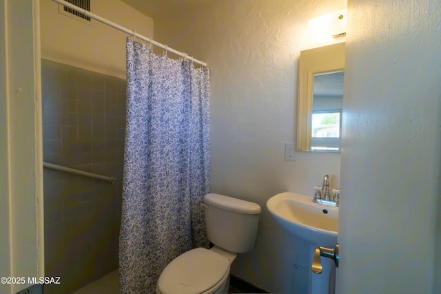 bathroom featuring visible vents, tiled shower, and toilet