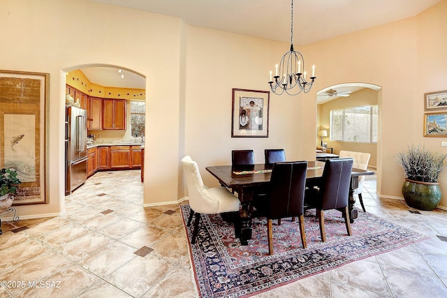 dining space with baseboards, arched walkways, and a chandelier