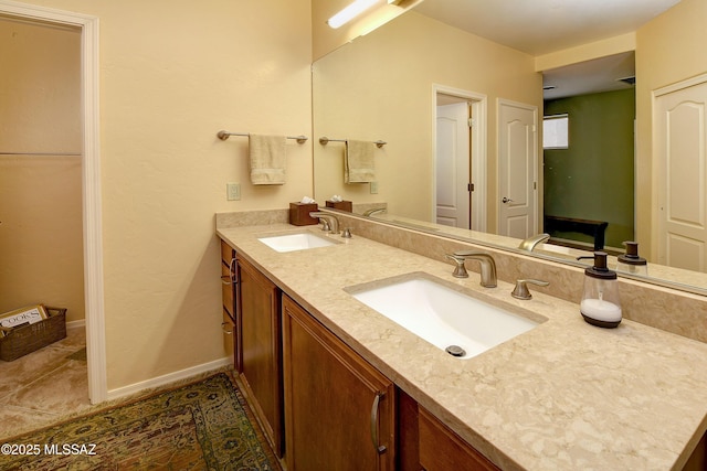 bathroom featuring double vanity, tile patterned flooring, a sink, and baseboards