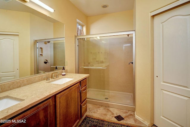 full bathroom with a stall shower, double vanity, a sink, and tile patterned floors