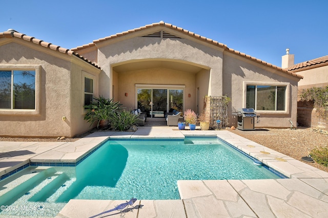 back of house featuring a patio area, an outdoor pool, and stucco siding