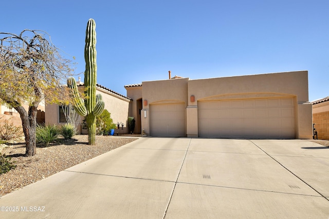 pueblo-style house with a garage, concrete driveway, and stucco siding