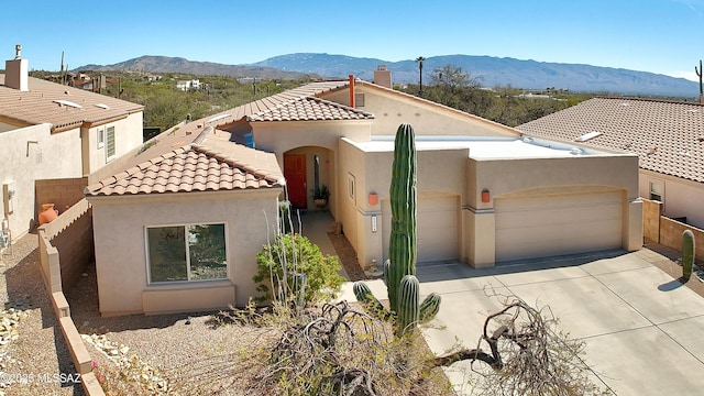 view of front of property featuring concrete driveway, an attached garage, a mountain view, and stucco siding