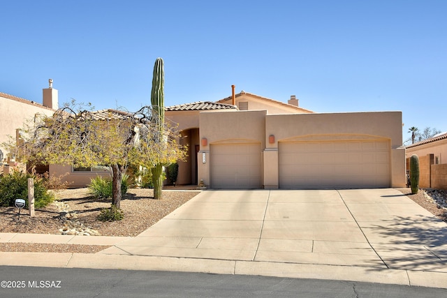 view of front of house with an attached garage, a tiled roof, concrete driveway, and stucco siding