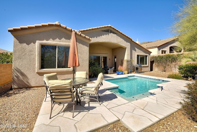 back of property featuring an outdoor pool, a patio, a tiled roof, and stucco siding