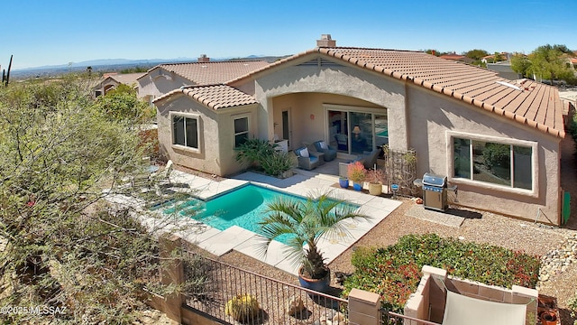 back of house featuring a patio, fence, a tiled roof, a fenced in pool, and stucco siding