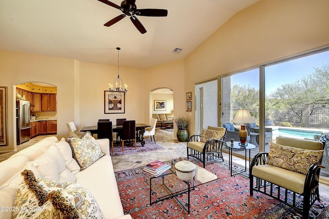 living area with arched walkways, ceiling fan with notable chandelier, and visible vents